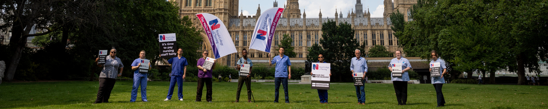 Image of ten nurses holding 'Fair Pay for Nursing' campaign materials, standing in front of the Houses of Parliament