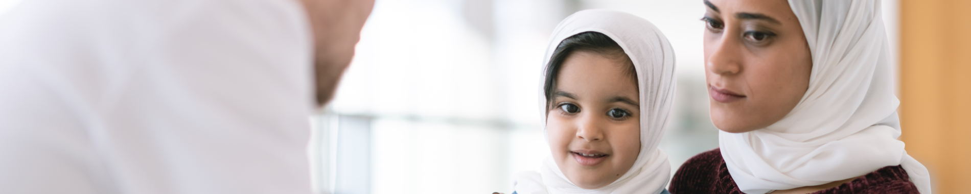 Woman and daughter wearing Hajibs talking to a healthcare professional