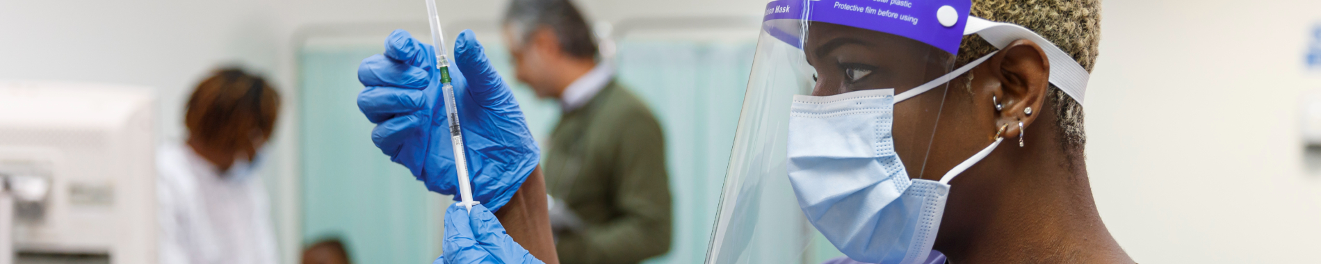 Nurse wearing protective face gear and mask holding needle