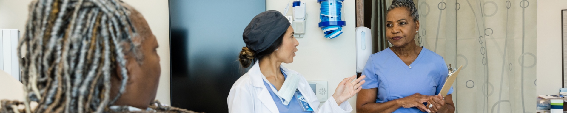 Older nurse talking to a patient and doctor