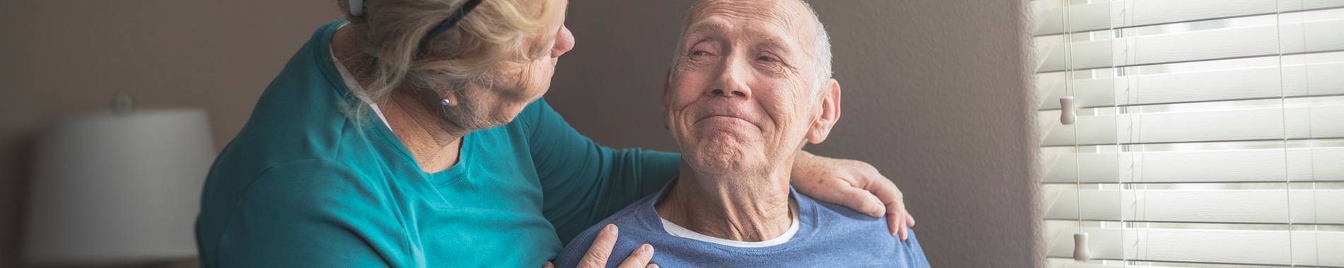 woman putting hands on elderly man's shoulders