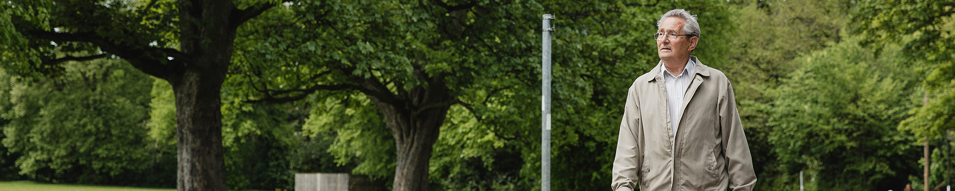 elderly man walking by trees