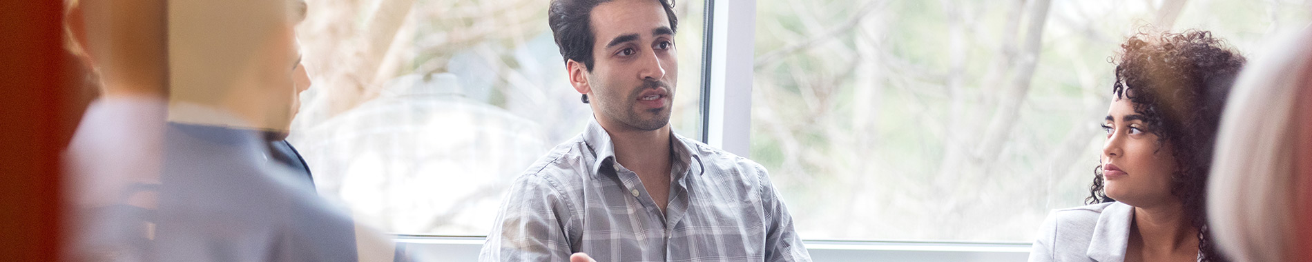 man sitting and talking to a group of people 