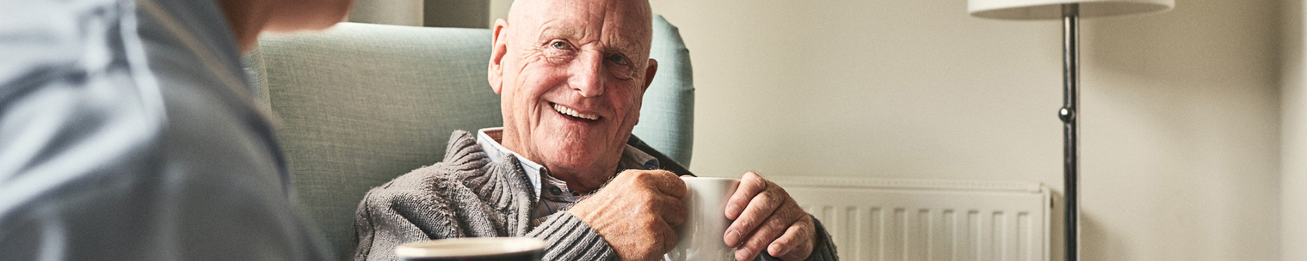 elderly man drinking tea with nurse