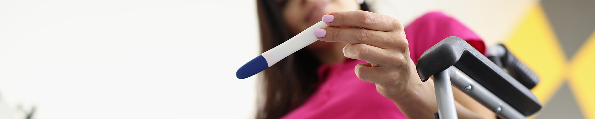 woman in wheelchair looking at pregnancy test