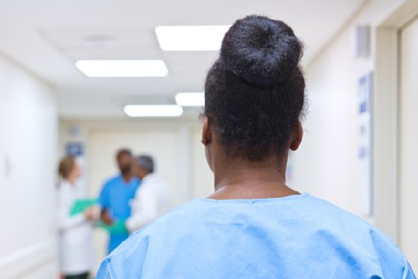 Back view of female nurse standing in hospital corridor