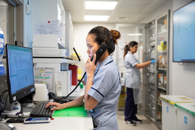 Nurse speaking on the phone and working on a desktop computer