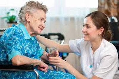 Palliative care nurse attending to an elderly patient in a wheelchair in a care home
