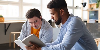 A man reading a book and showing it to another man