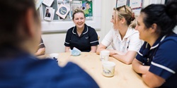 Principle B Image of nurses smiling and talking around a table