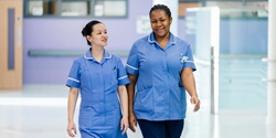 Principle D Two smiling nurses walking down a corridor
