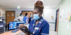 Principle E Nurse wearing a facemask and looking at a digital tablet