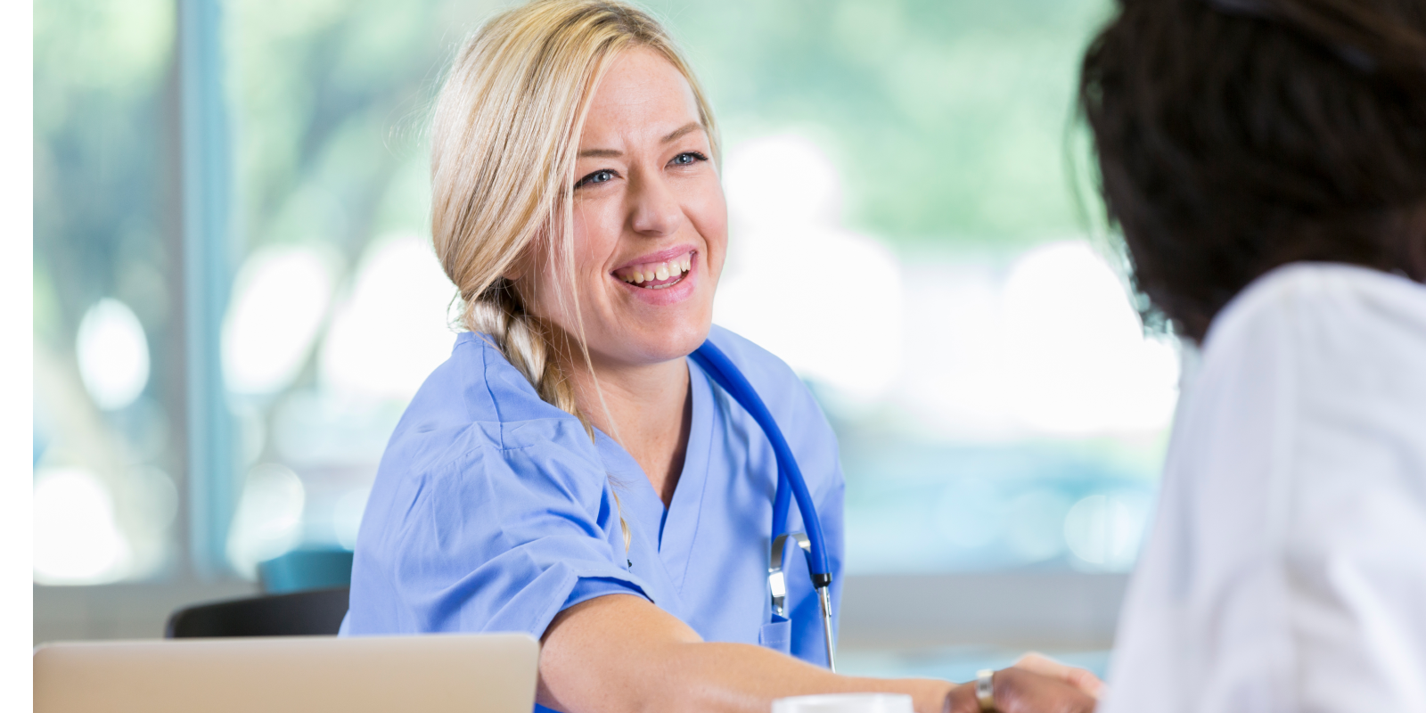 Nurse at interview Female nurse smiling as she shakes hands across a table with another medical professional