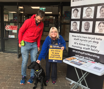 Nicky Hughes poses with dog and its owner at University Hospital Wales pay campaign photo