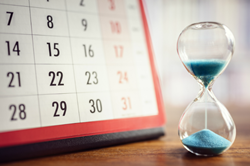 paper calendar and hourglass on table