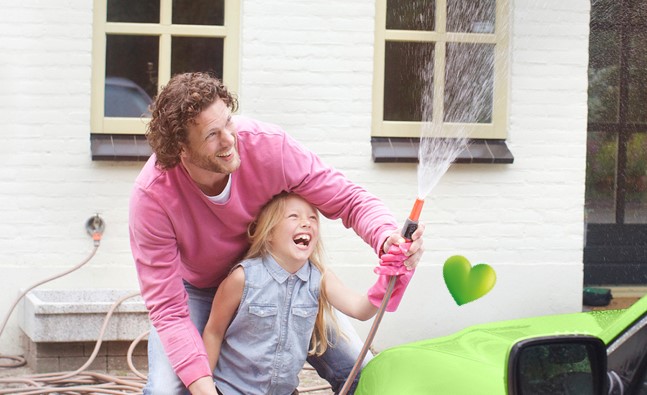 a father and daughter squirting water from a hose