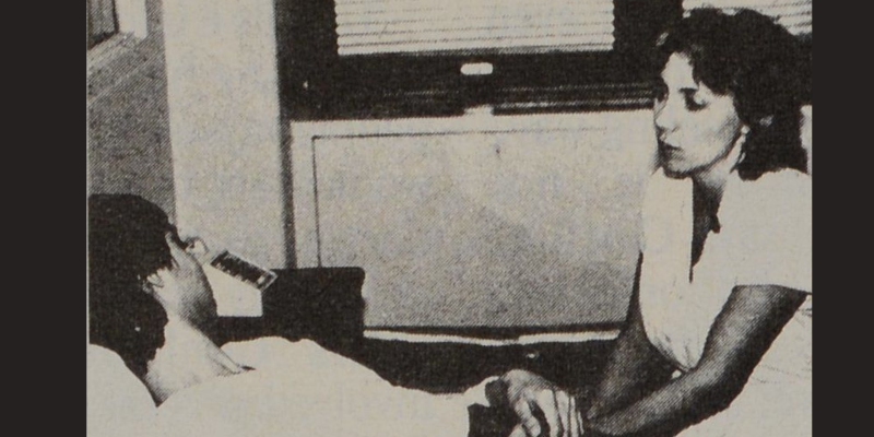 Black and white newspaper image of a nurse sitting by the bed of an Aids patient.