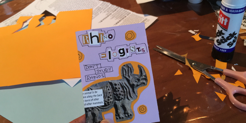An image of part of a purple zine entitled "Rhinologists don't study rhinos", showing a rhino ,held over a table with collaging materials.