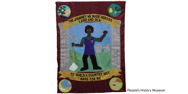 A protest banner by Seleena Laverne Daye  (2021). Text reads: 'The Journey We Made Across Land And Sea, To Build A Country Not Made For Me'.