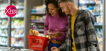 a man and woman shopping in a supermarket. the woman is holding a full shopping basket. there is an rcn xtra logo in the top left-hand corner