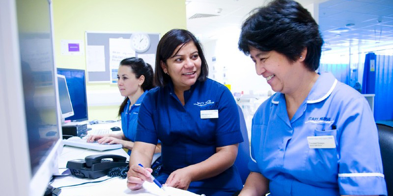 Three nurses sitting at a computer desk