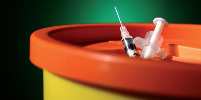 Sharps bin with needles sticking out