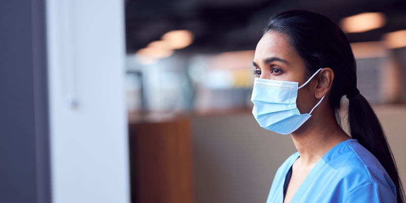 A female nurse wearing a face mask looks concerned