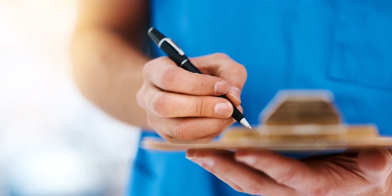 Close up on nurse's hand signing a document on a clipboard