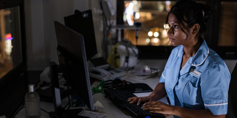 Member of nursing staff working at a computer late at night