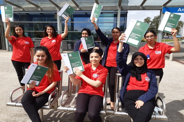 Cadets sitting together waving their workbooks