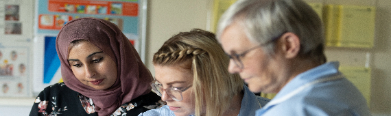 consultant nurse looking at notes with two other nurses 