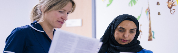 two female nurses comparing notes in a pediatric clinical setting 