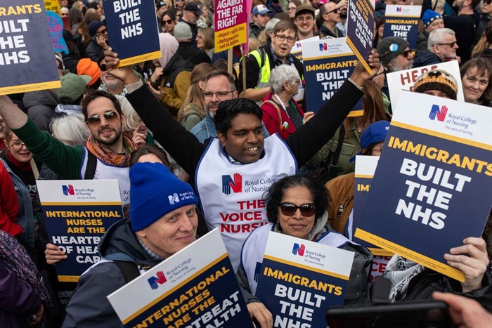 A photograhp of Bejoy Sebastian with his arms raised in celebration, surrounded by RCN members and placards at the Together Alliance demo in London on 280326