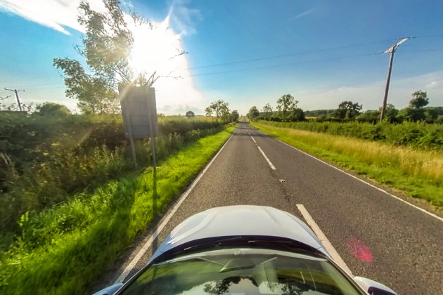 Car driving down a clear road on a sunny day