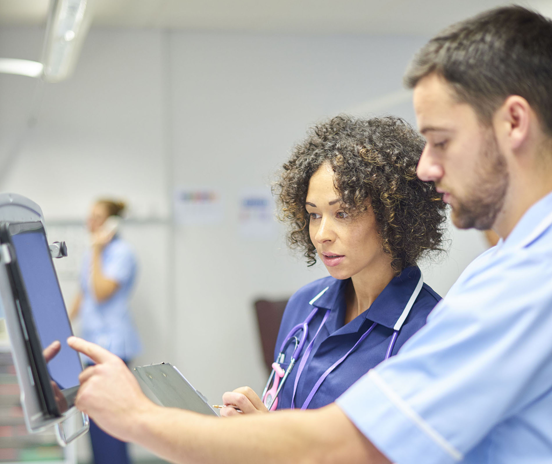 Two nurses check medication dosage on a tablet