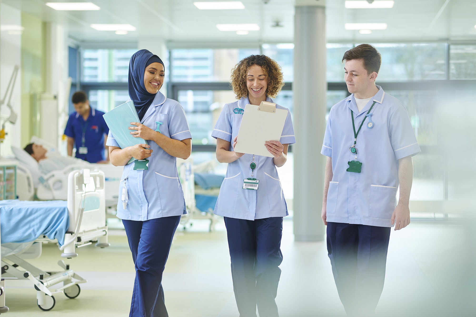 Three nursing students smiling in hospital corridor