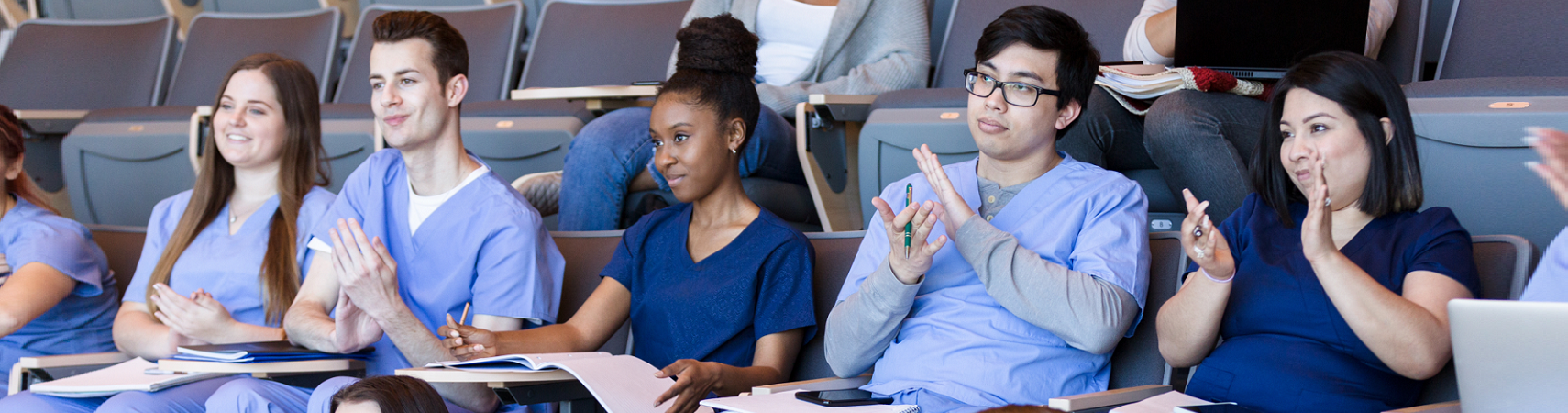 Student nurses in a lecture theatre Student nurses in scrubs sat in a lecture hall with their notes in front of them
