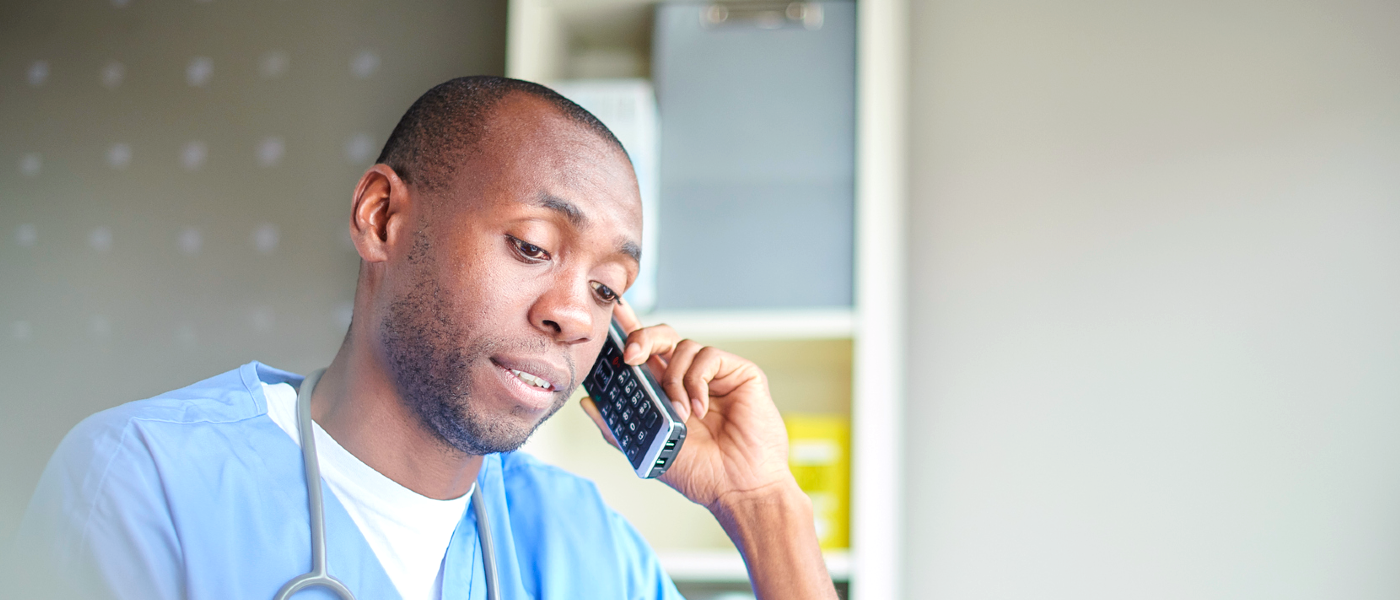 Black male nurse in scrubs talking on the phone