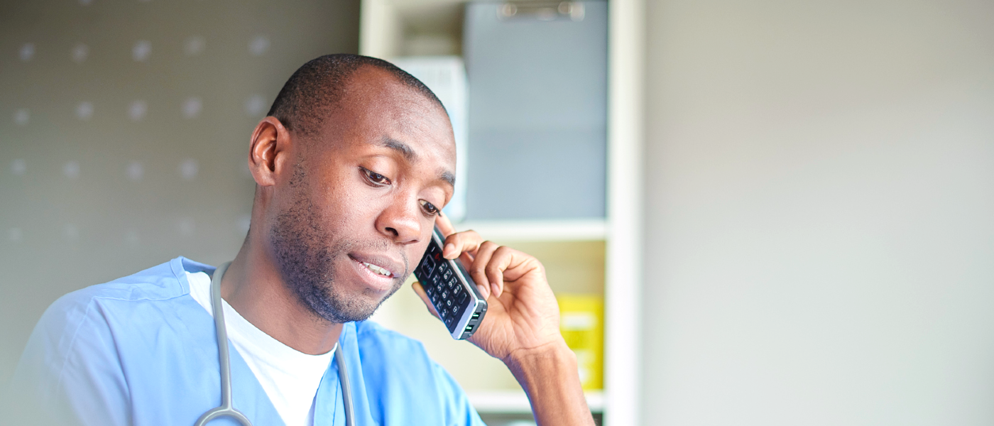 Male nurse on phone Black male nurse in scrubs talking on the phone