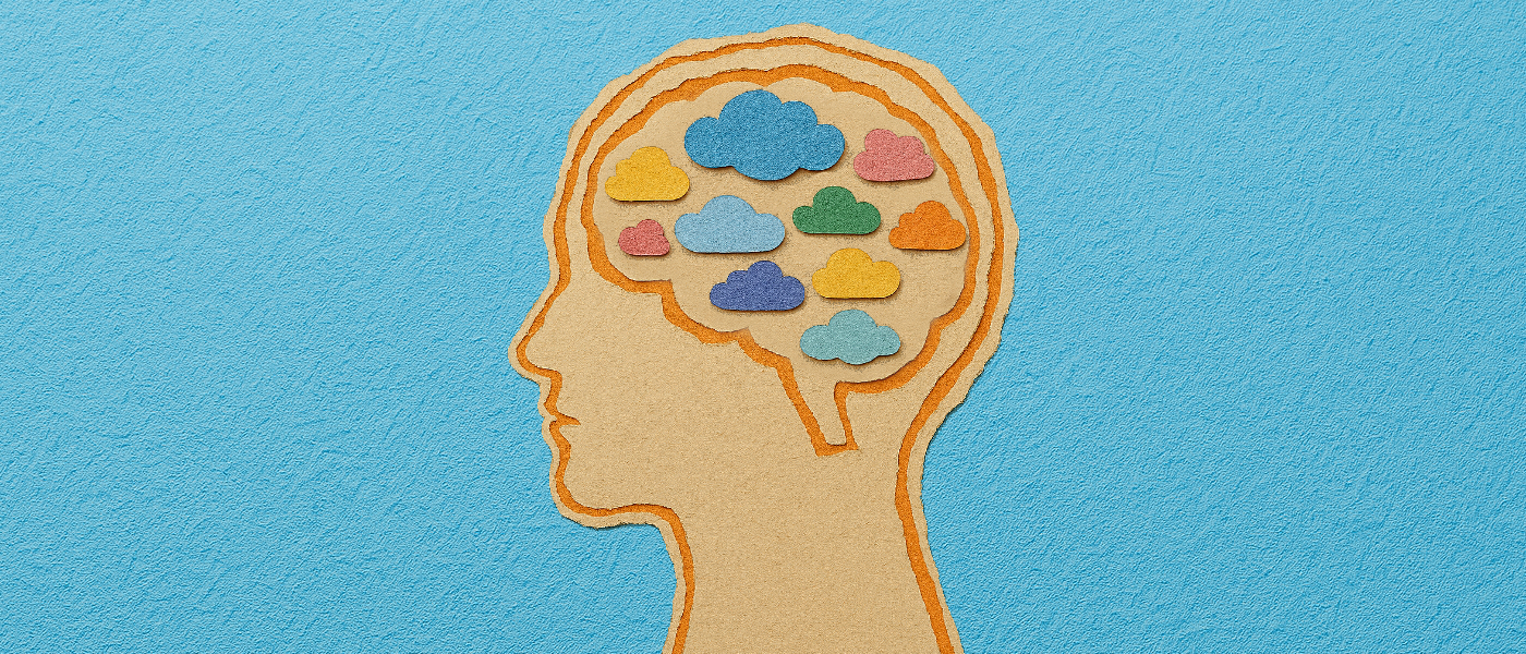 A scrapbook-style illustration of a human head in profile, with the brain area filled with small, folded paper clouds in a variety of bright colours.
