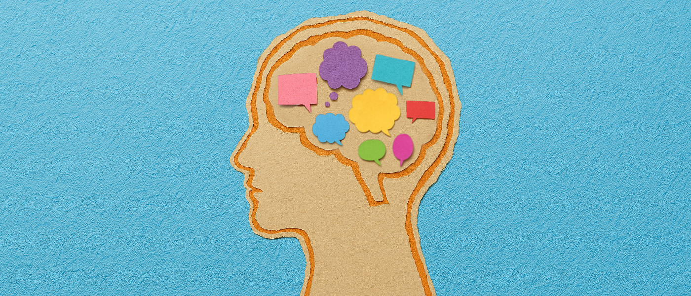 A scrapbook-style illustration of a human head in profile, with the brain area filled with small, speech bubbles and thought bubbles made from paper in a variety of bright colours.