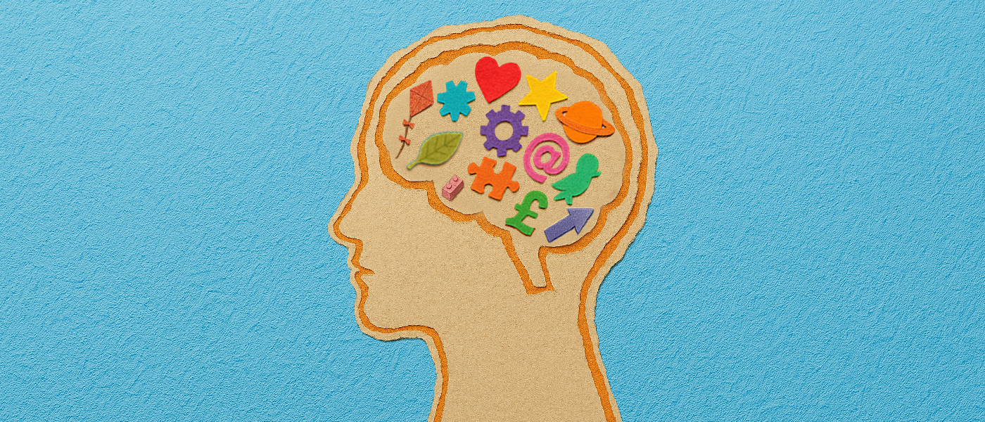 A scrapbook-style illustration of a human head in profile, with the brain area filled with small, folded paper symbols in a variety of bright colours.