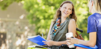 Lady in wheelchair talking to friend and smiling