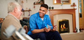 Male nurse sitting on sofa with elderly man