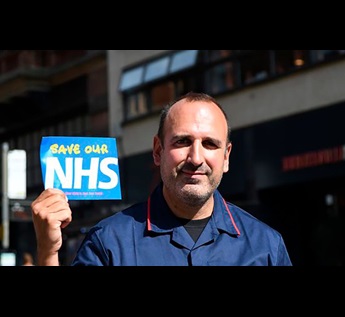 Photo of Joan in his nursing uniform holding a 'save the NHS' sign