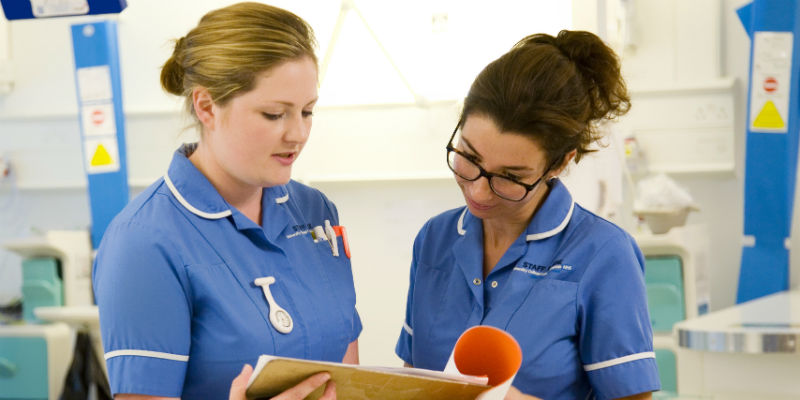 Two nurses on an acute ward looking at patient notes