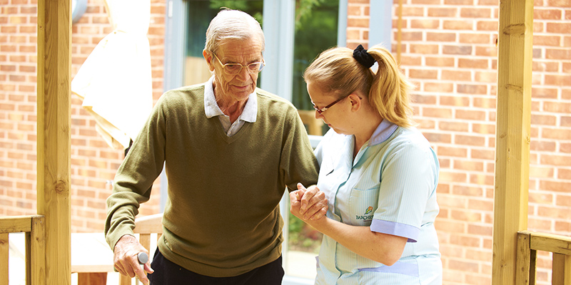 Older man being supported by a care worker