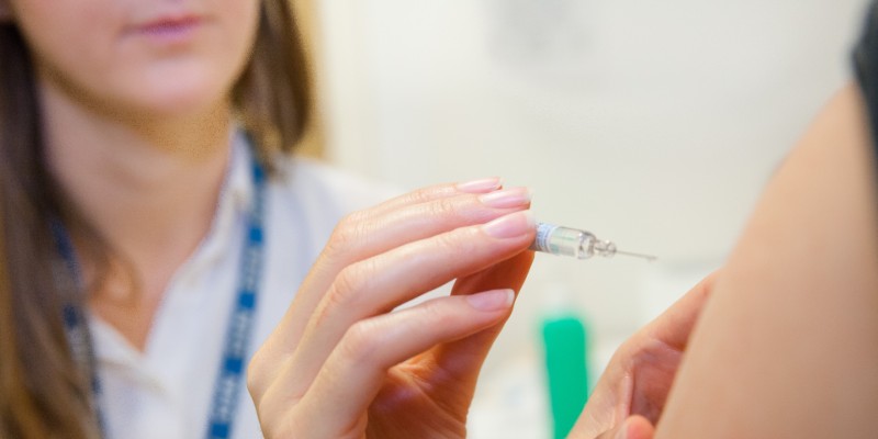 A nurse gives an injection in someone's arm