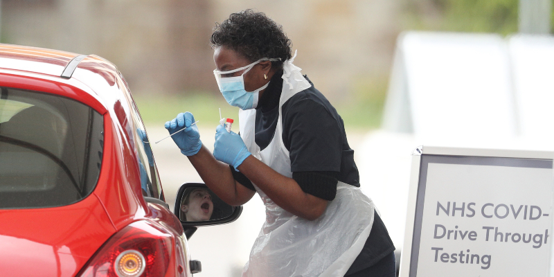 A health care worker tests someone for COVID-19 at a drive through testing service