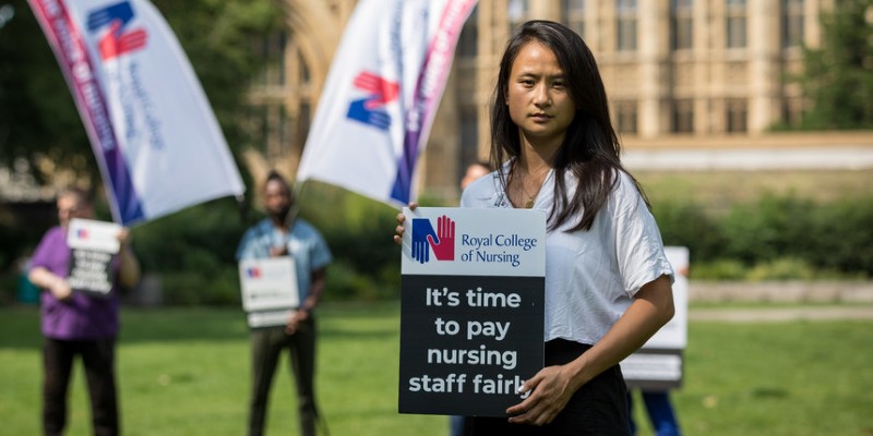 RCN member Carmen Sumadiwiria holds a Fair Pay For Nursing sign at a demo at Westminster in summer 2021